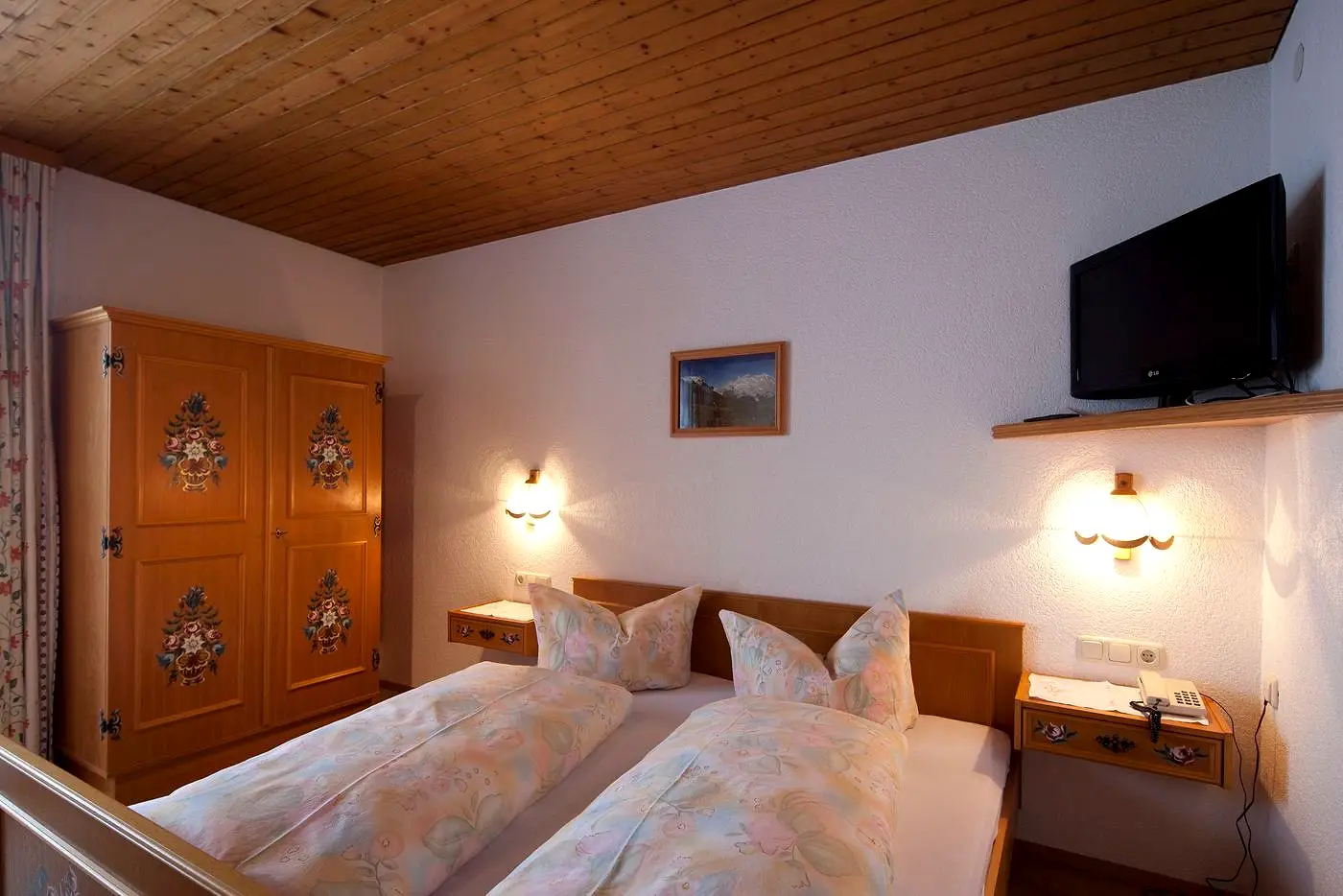 Schlafzimmer mit Doppelbett, bemaltem Bauernschrank und Holzdecke