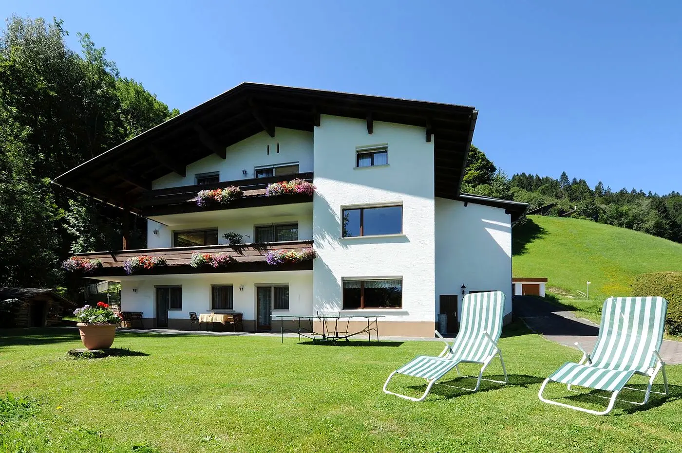 Das Haus Schwarzhorn im Sommer, davor Liegestühle im Garten